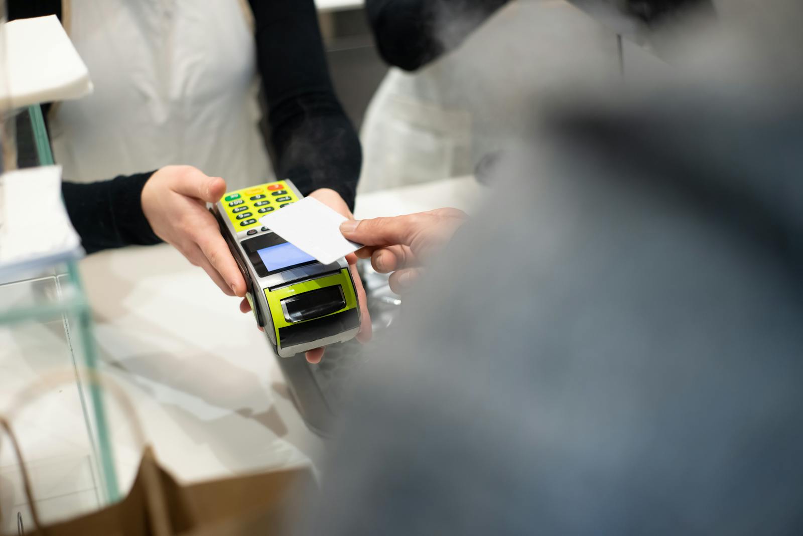 Customer paying by card on a handheld payment terminal at the till.